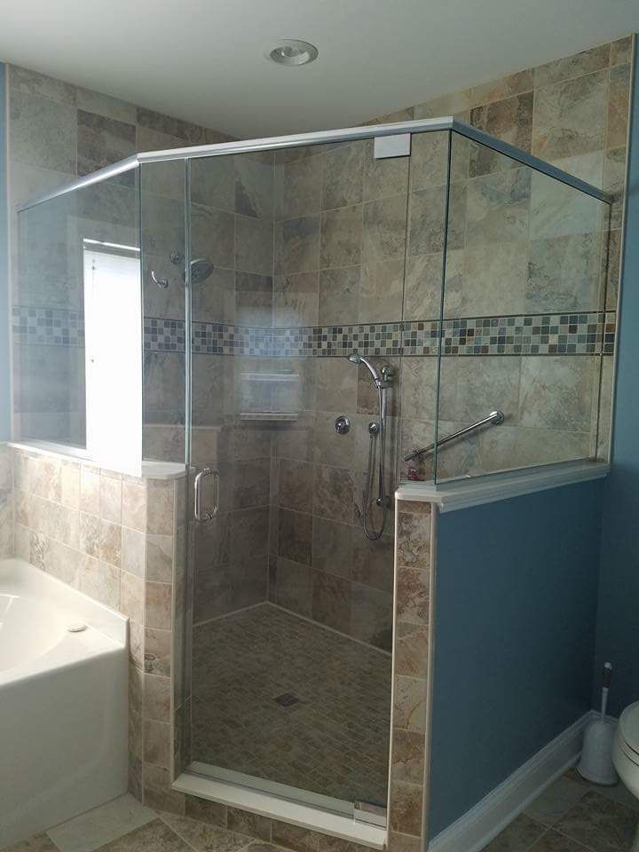A bathroom with a walk in shower with a glass door.