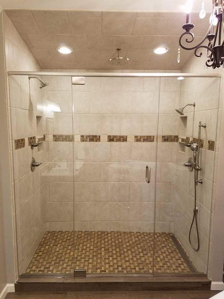 A bathroom with a walk in shower with a glass door.