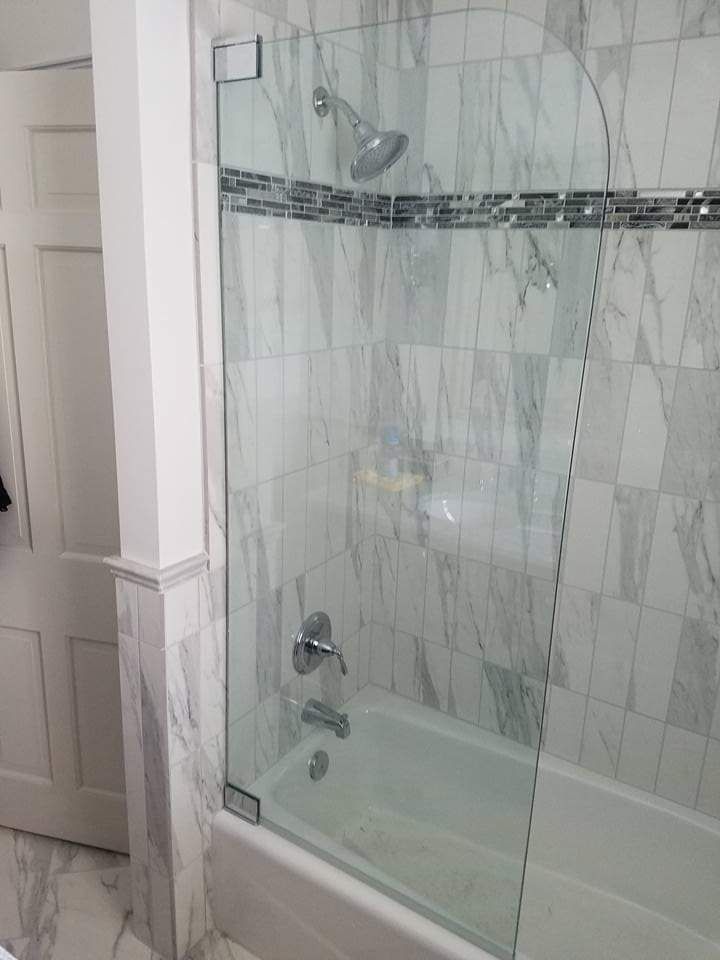A bathroom with a bathtub and a shower with a glass door.