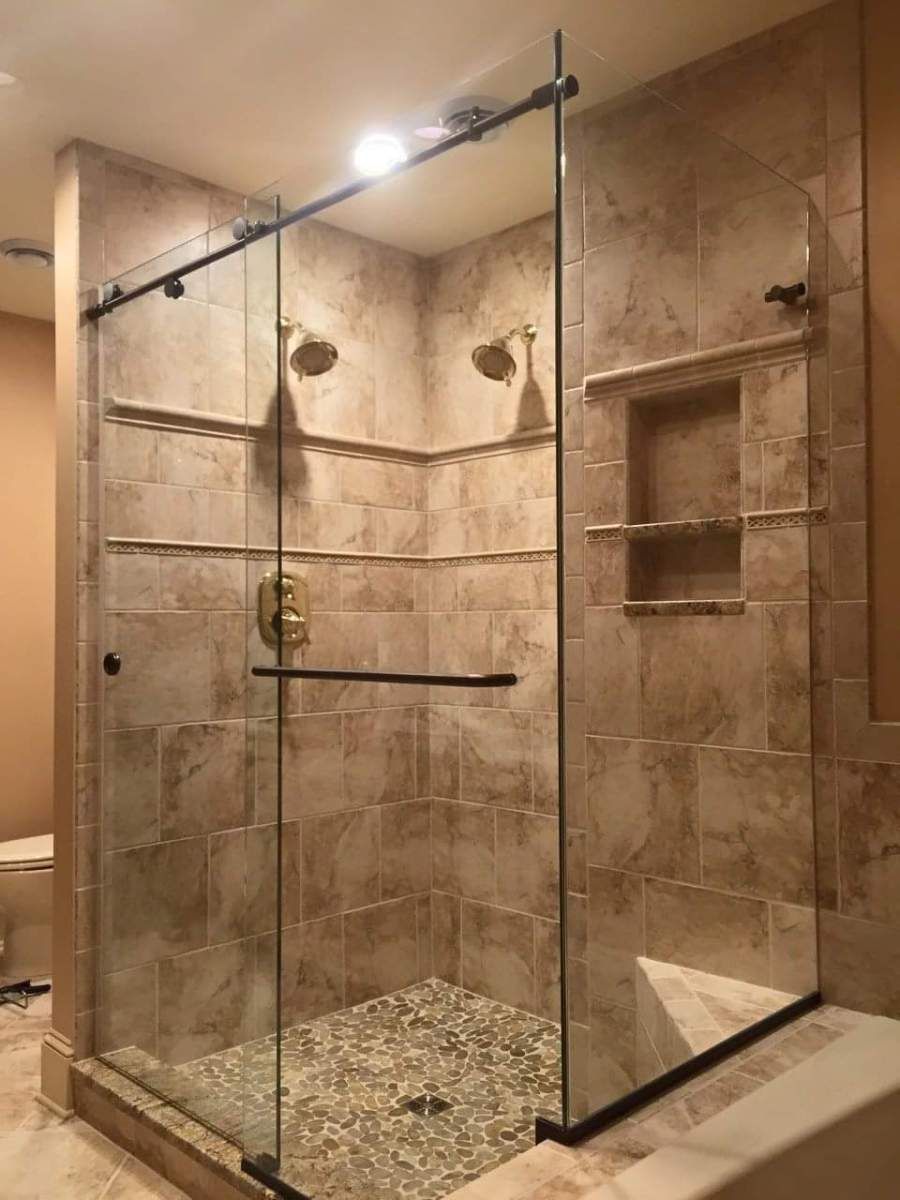 A bathroom with a walk in shower with sliding glass doors.