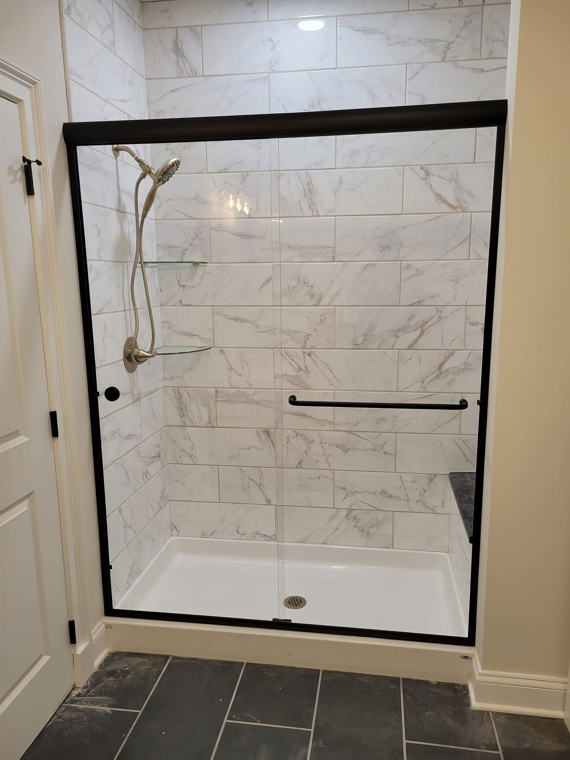 A bathroom with a sliding glass shower door and a shower head.