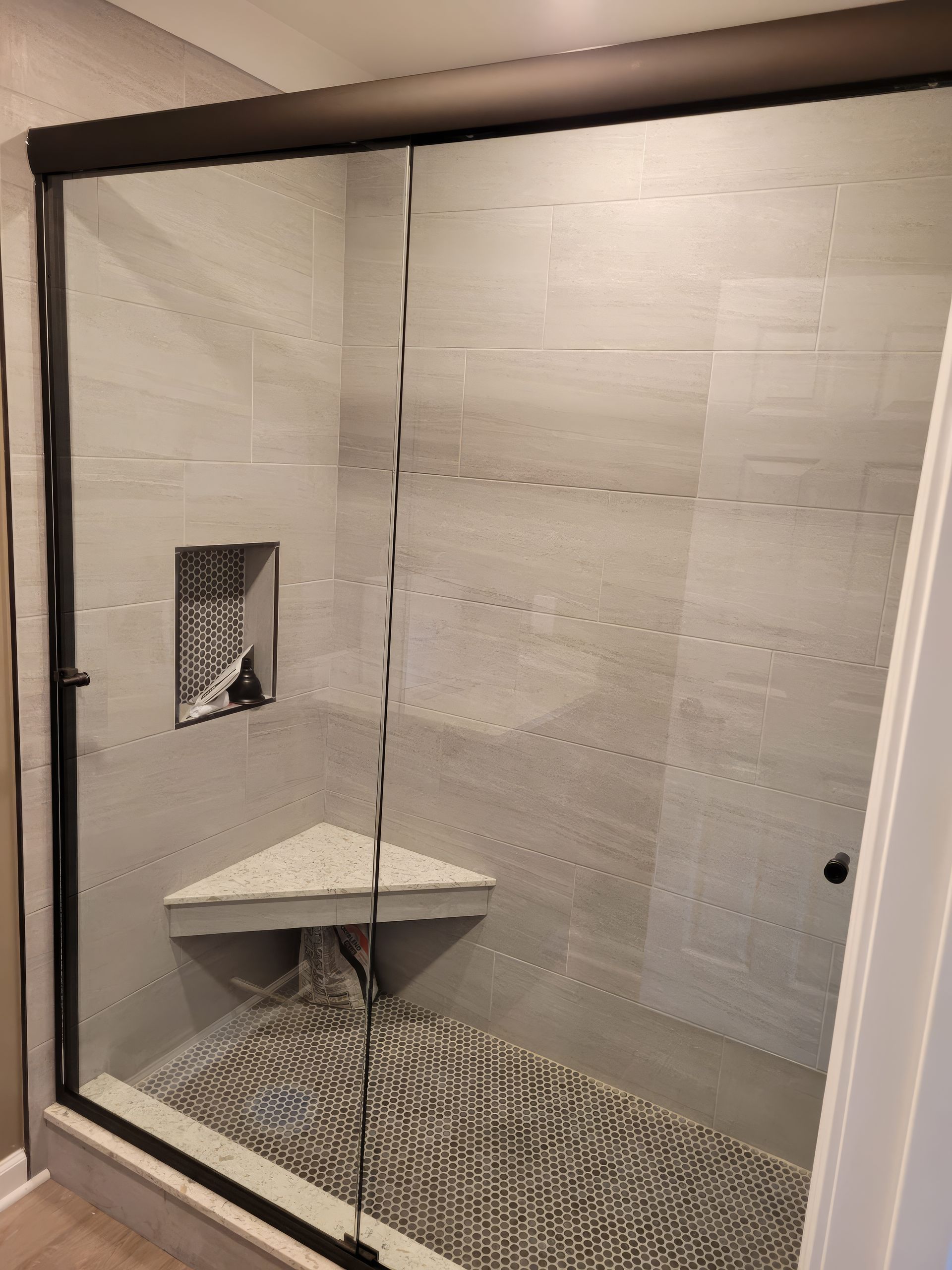 A bathroom with a sliding glass shower door and a bench.