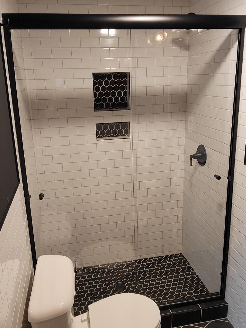 A bathroom with a toilet , shower , and sliding glass door.