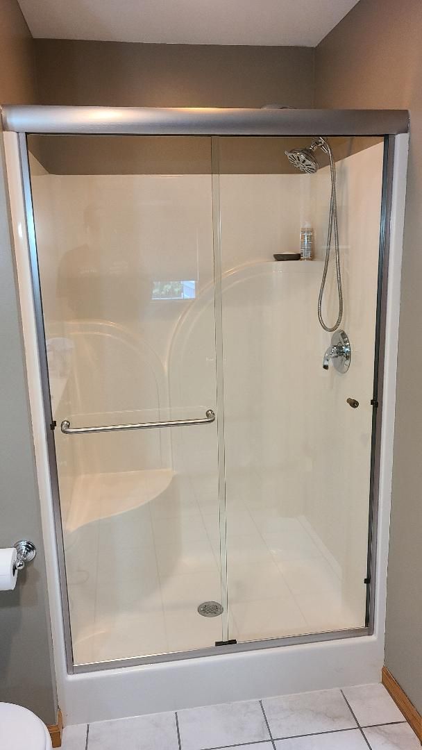 A bathroom with a sliding glass shower door and a toilet.