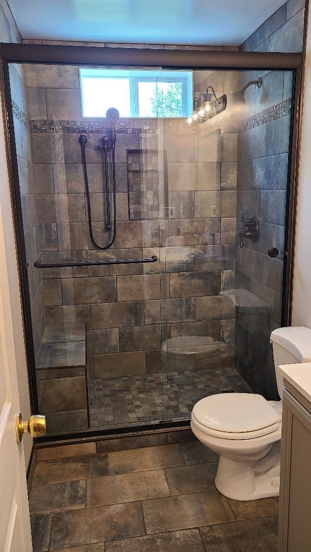 A bathroom with a toilet and a shower with a sliding glass door.