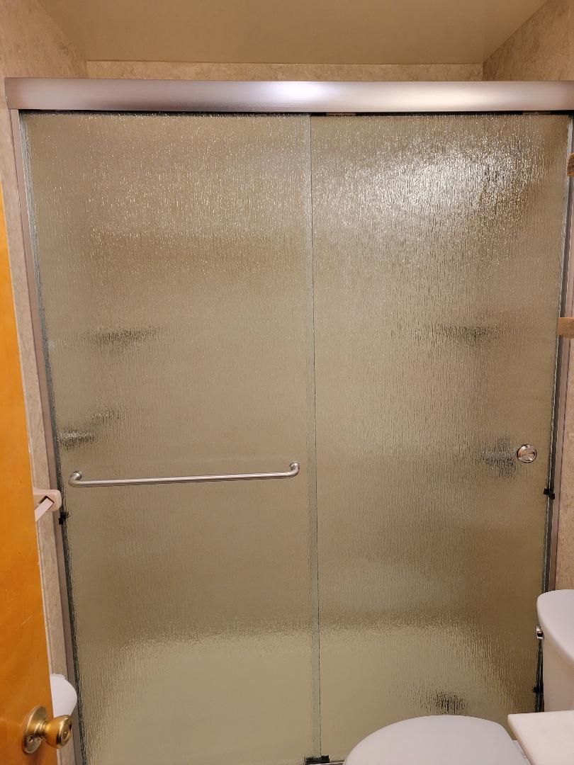 A bathroom with a sliding glass shower door and a toilet.