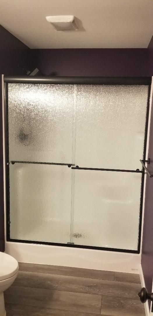 A bathroom with a sliding glass shower door and a toilet.