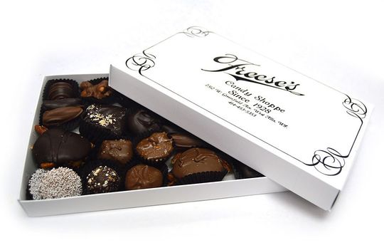 A white box filled with chocolates has the lid open