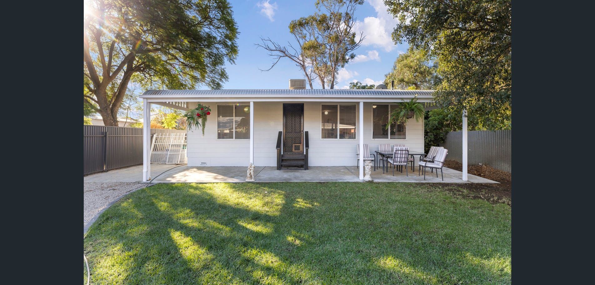 Small white house with a front porch and green lawn in sunlight