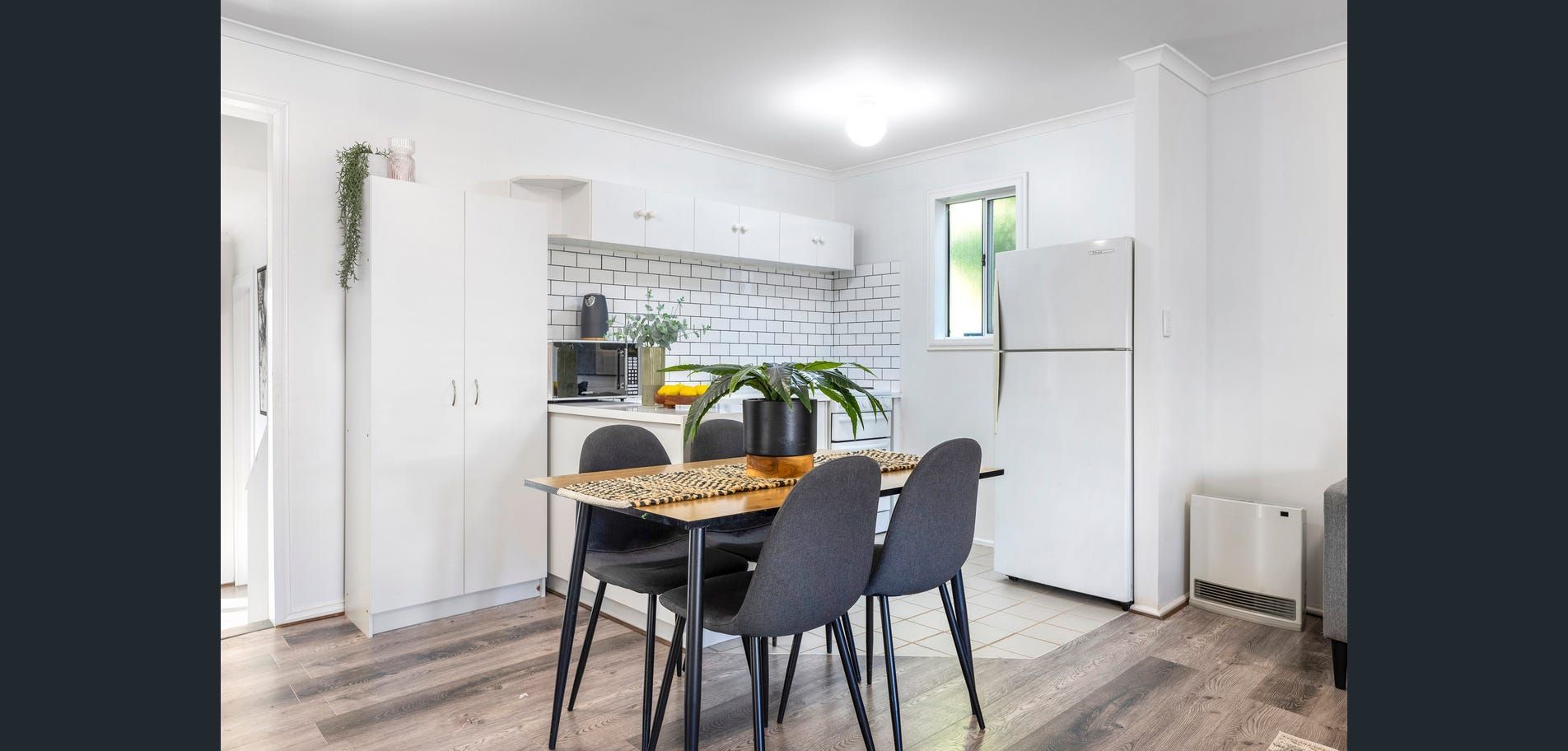 Bright dining nook with black chairs, round table, white brick wall, and indoor plants in a modern apartment