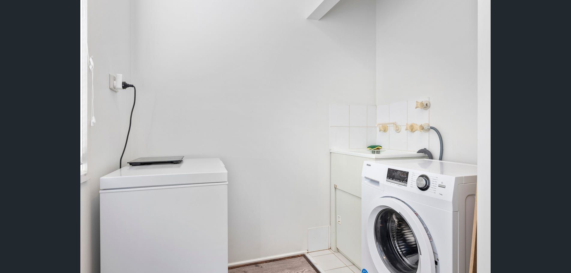 Laundry room with a washing machine, utility sink, and white walls
