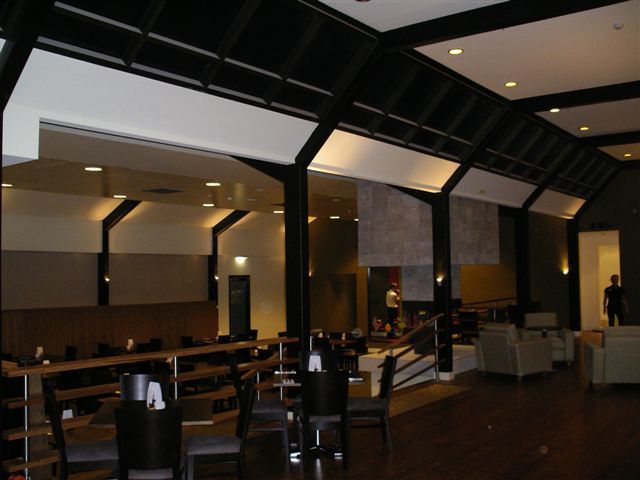 Modern restaurant interior with dark wood tables, booths, and warm pendant lighting