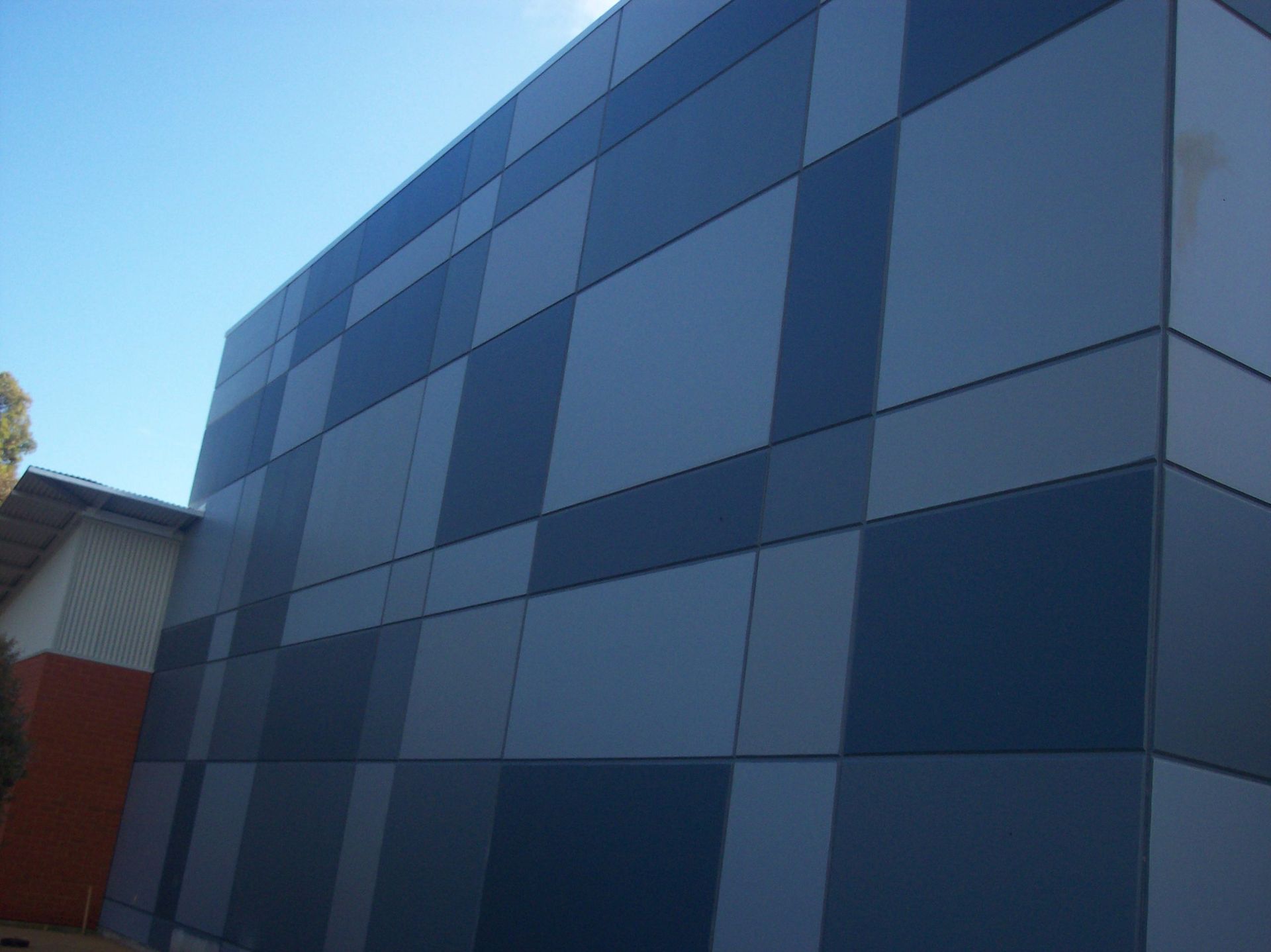 Blue and gray modern building facade with geometric panel pattern under a clear sky