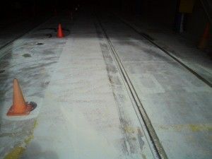 Snow-dusted road or parking lane with orange traffic cones and tire tracks at night