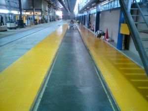 Empty indoor platform with yellow safety lanes beside a central walkway in a transit station