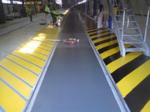 Yellow-and-black striped indoor ramp with a small object on the floor and a person in the distance