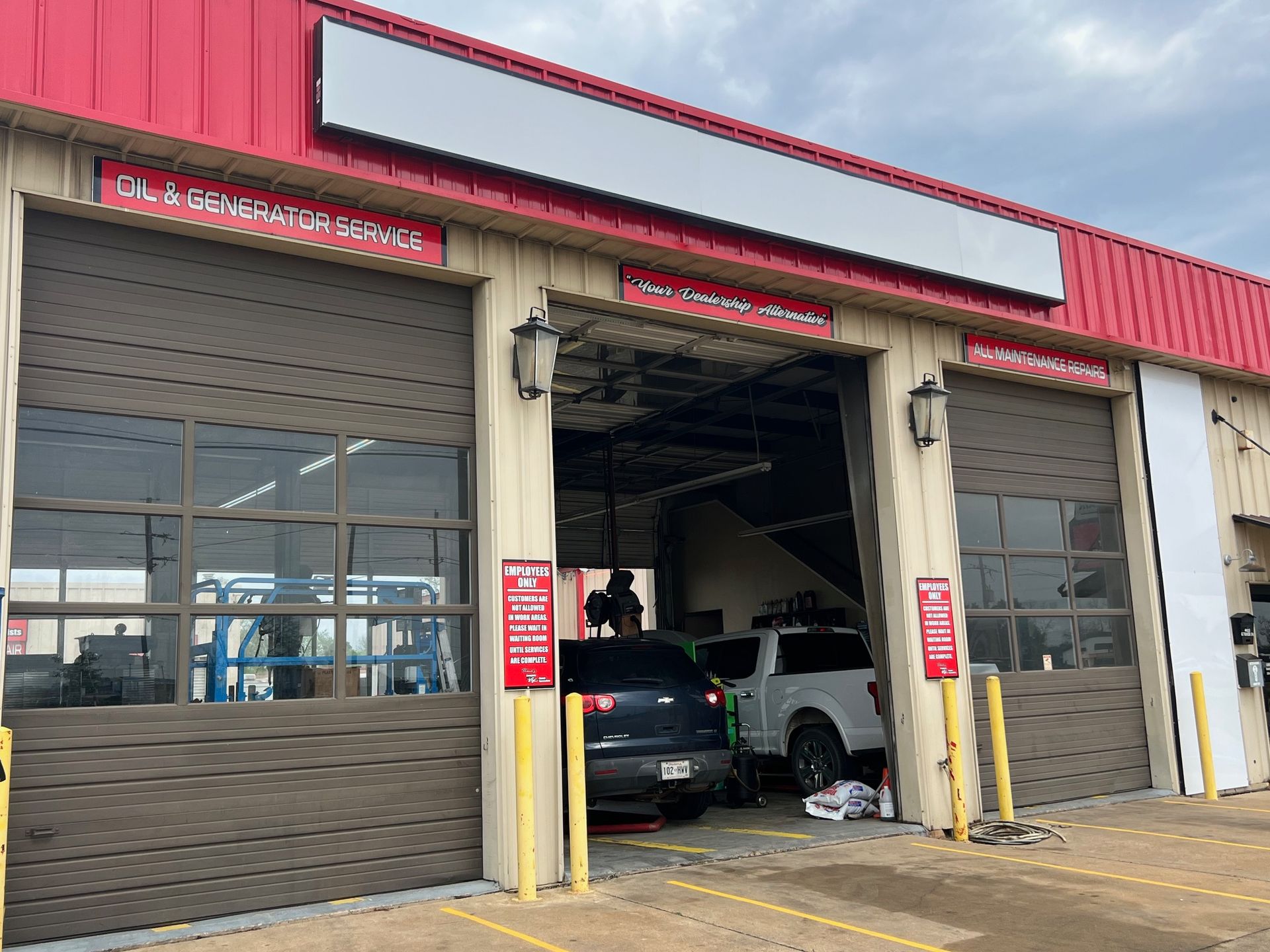 A car is parked in front of a garage with the doors open.