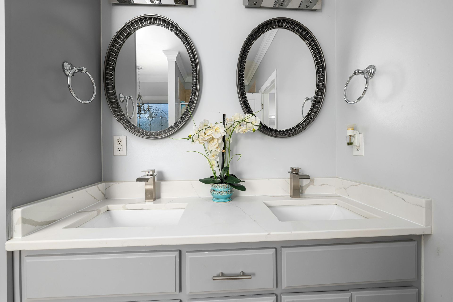 Under-sink plumbing with white pipes and two braided water supply lines inside a wooden cabinet