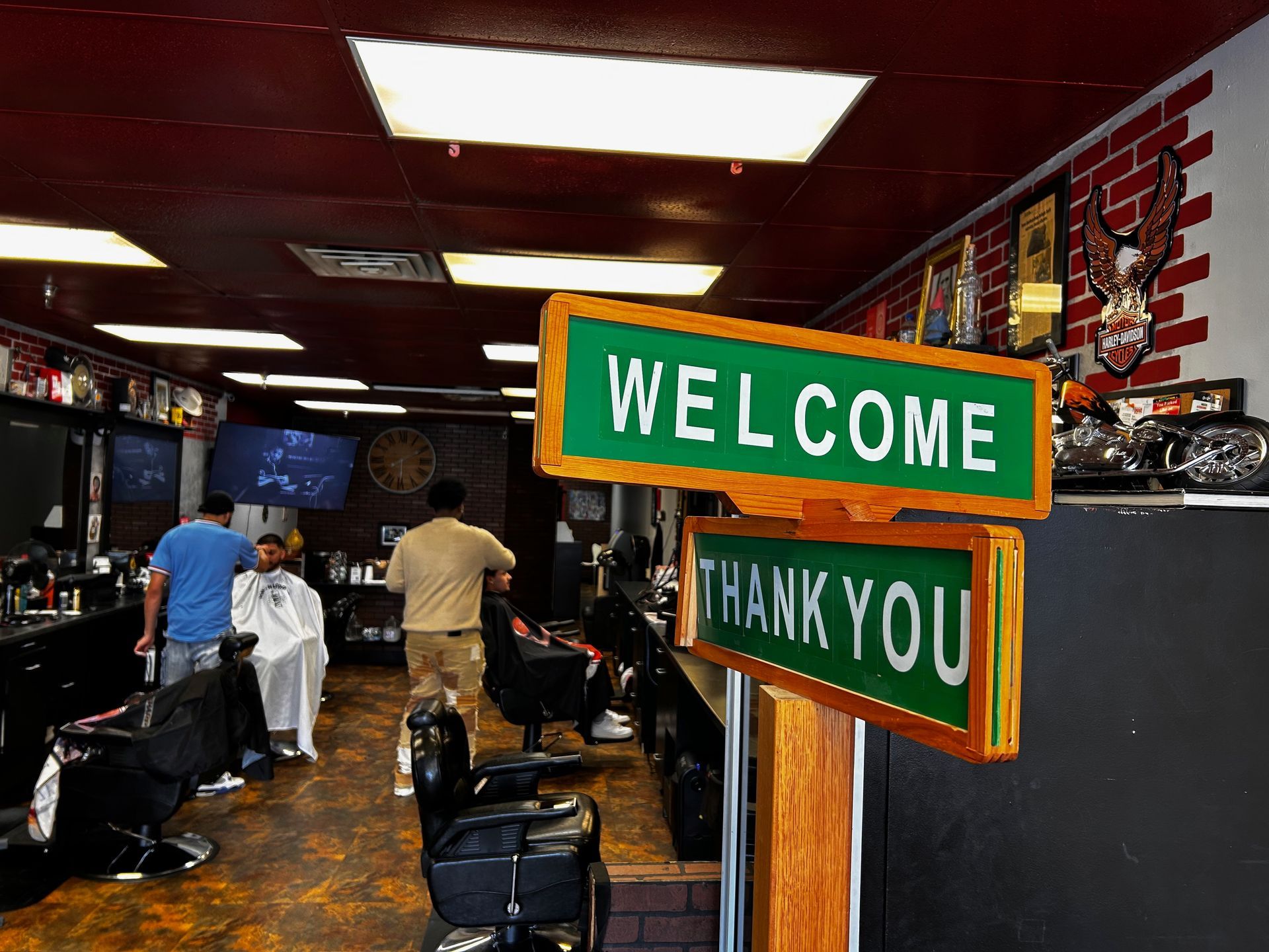 a barber shop with a welcome sign and a thank you sign