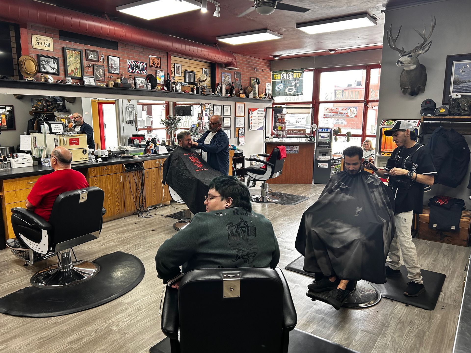 A group of people are getting their hair cut at a barber shop.