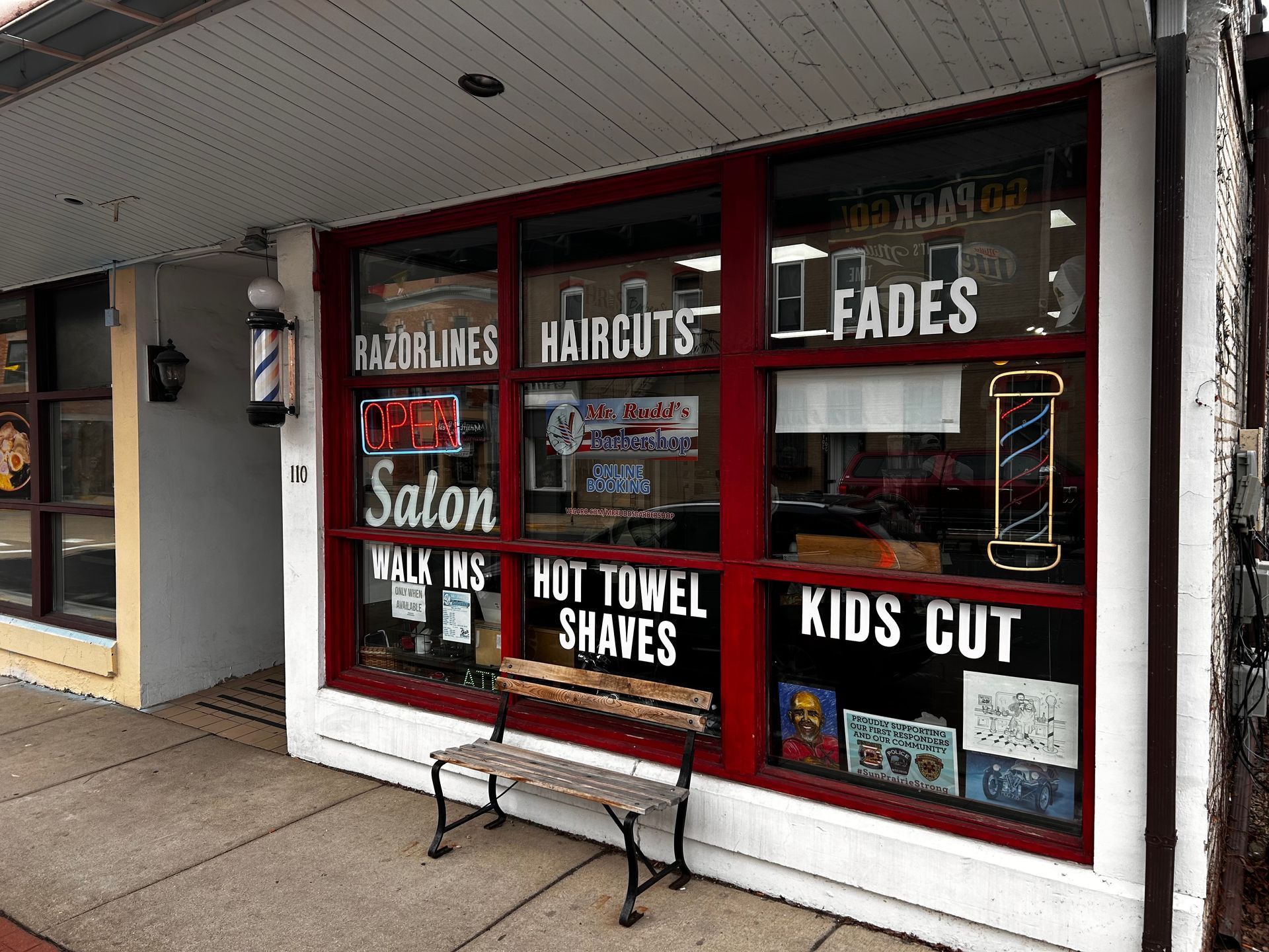A barber shop with a bench in front of it.