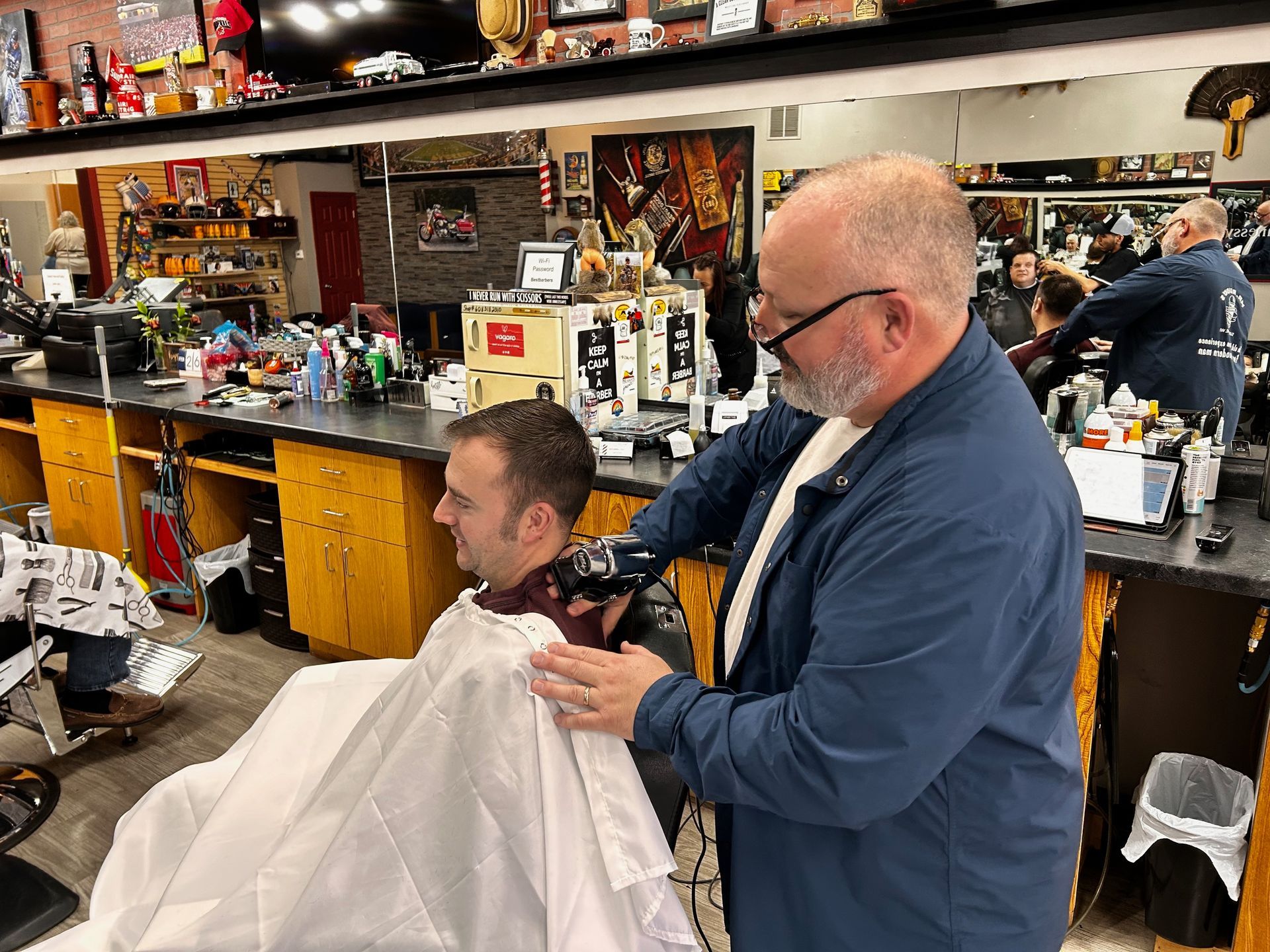 a man is getting his hair cut by a barber in a barber shop .