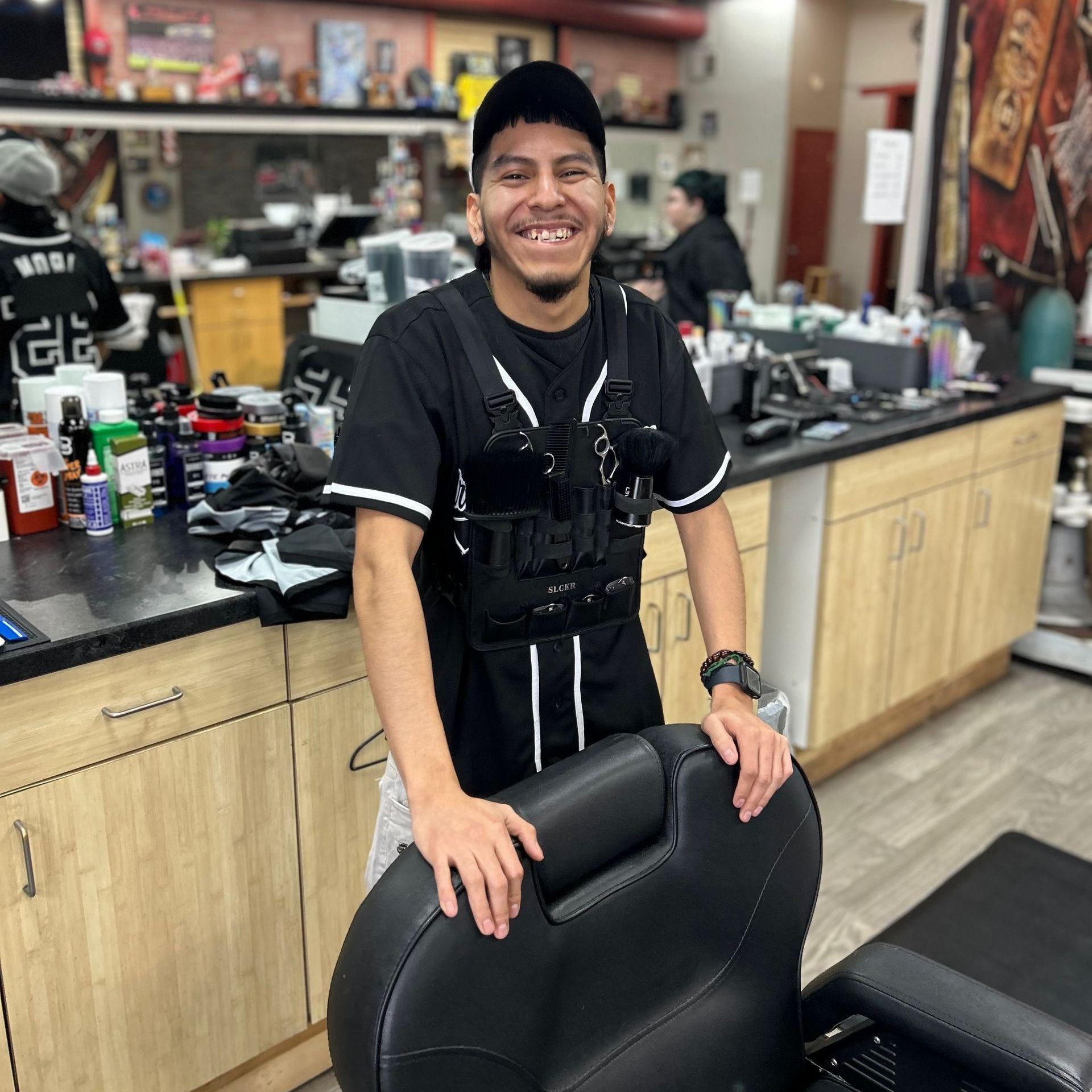 A man is standing next to a barber chair in a barber shop.