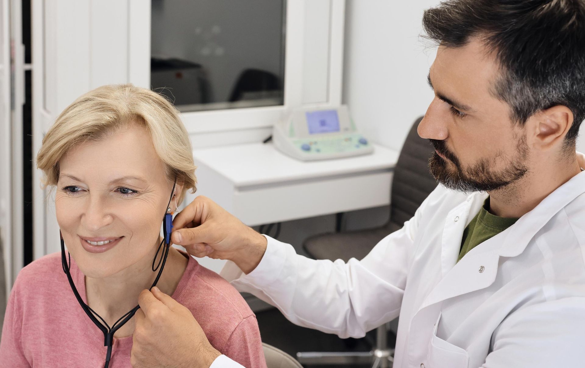 Doctor examining a smiling patient with a stethoscope in a clinic