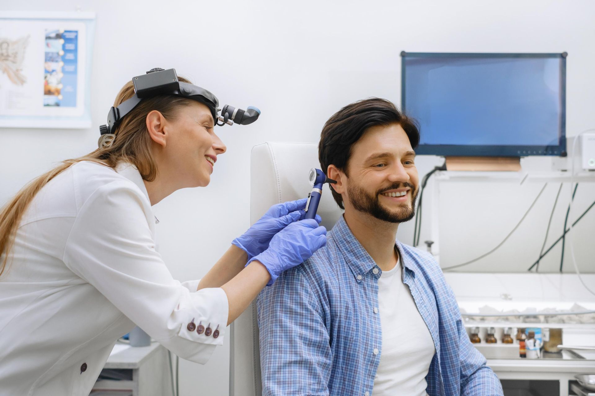 Doctor examining a smiling patient’s ear in a bright clinic room