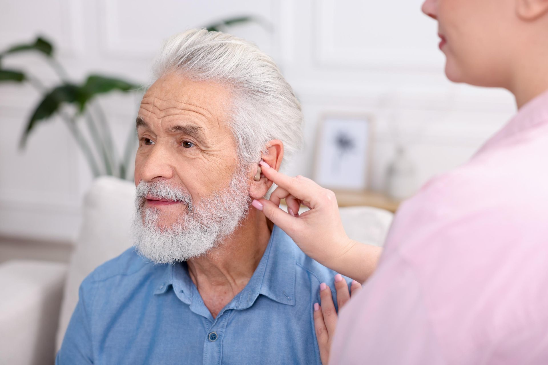 Healthcare worker examining an older man’s ear in a bright clinic