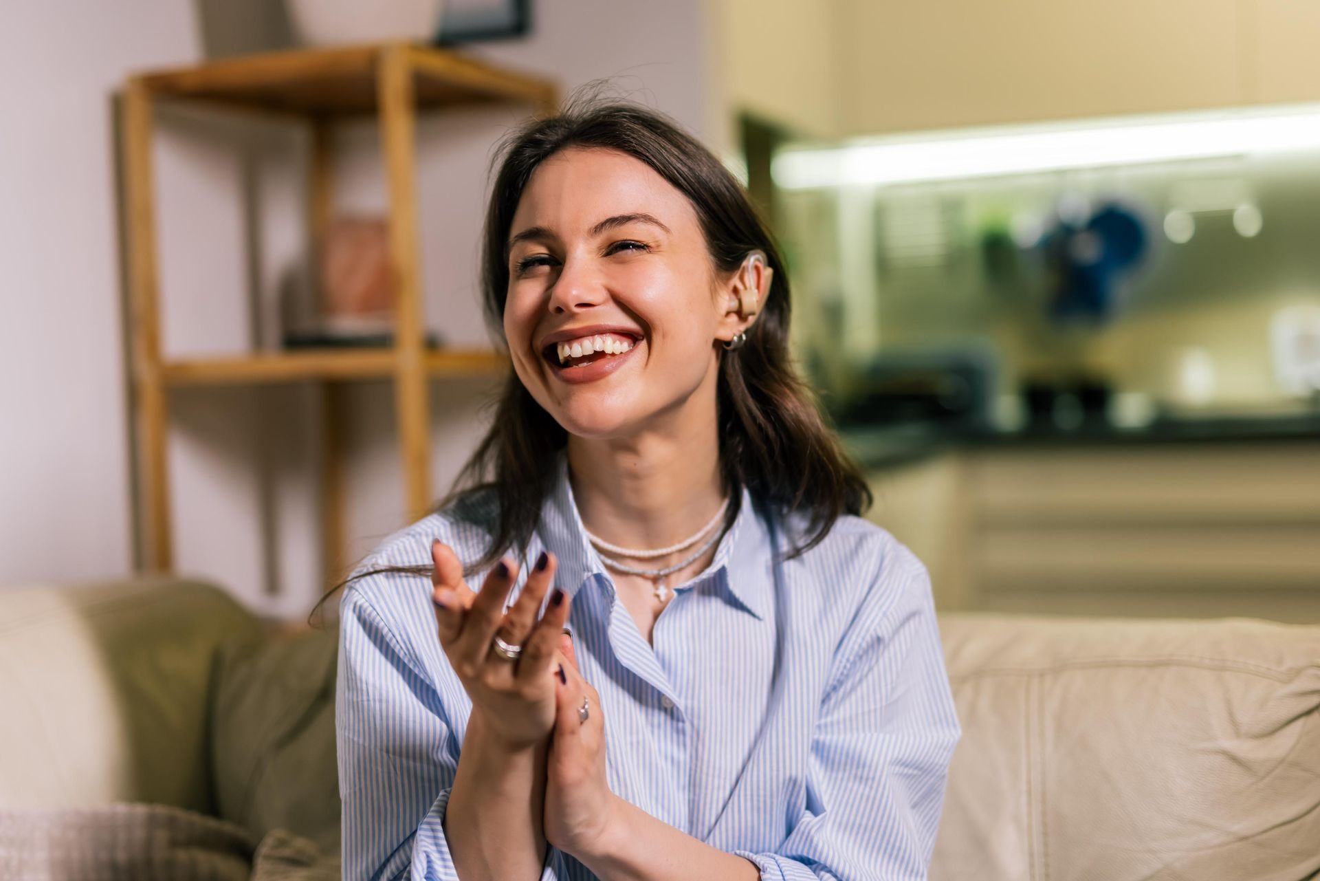 Smiling woman clapping on a couch in a bright living room