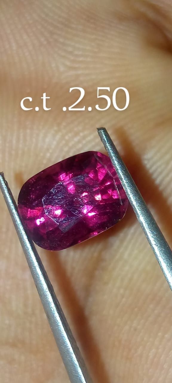 Roze facetgeslepen edelsteen, vastgehouden met een pincet, gemerkt met 