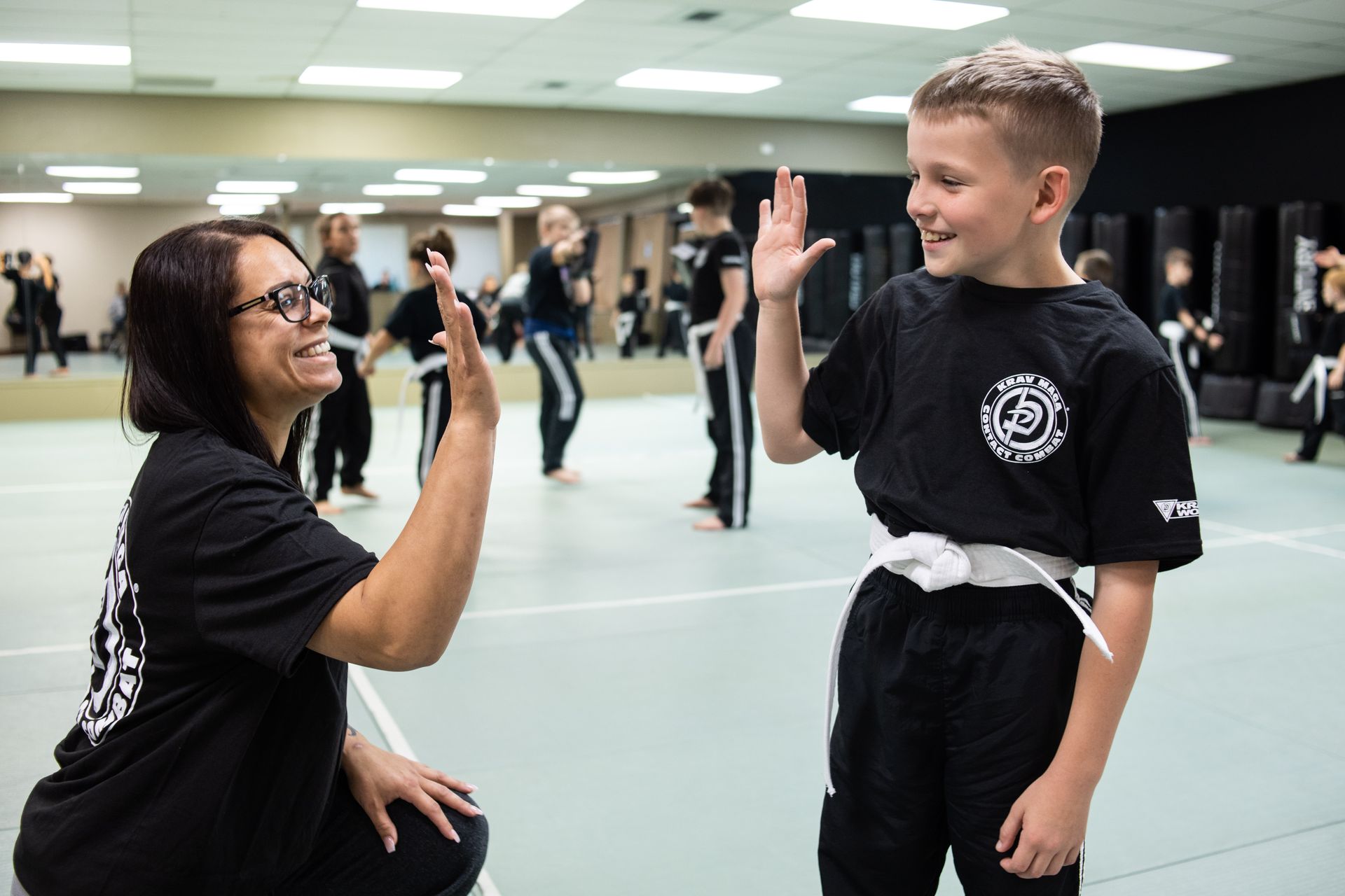 martial arts parent gives student in kids class a high five.
