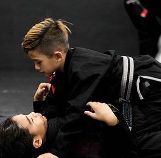 two students in class practicing jiu jitsu in the side control position