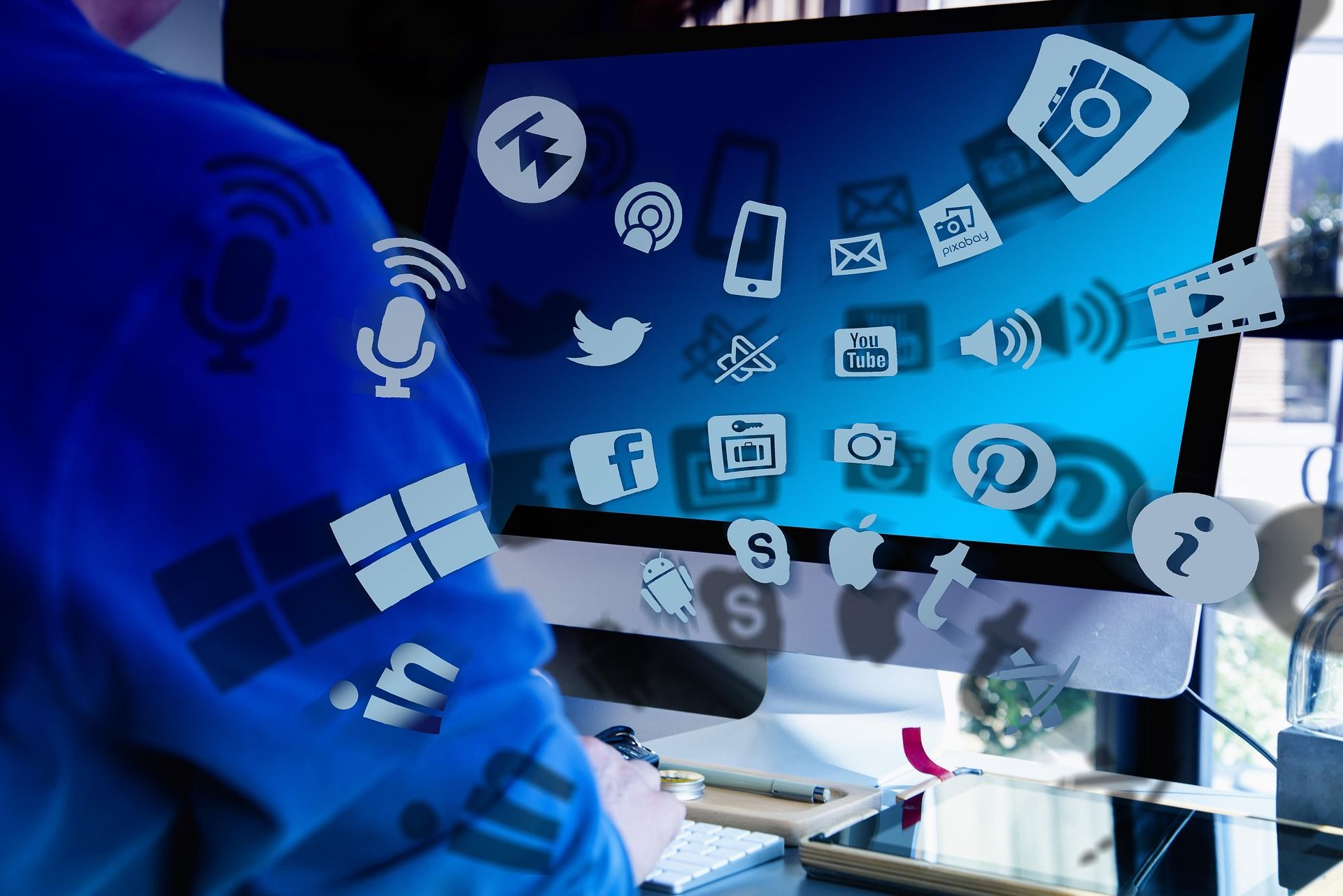 Person using a computer with floating social media and app icons on the screen