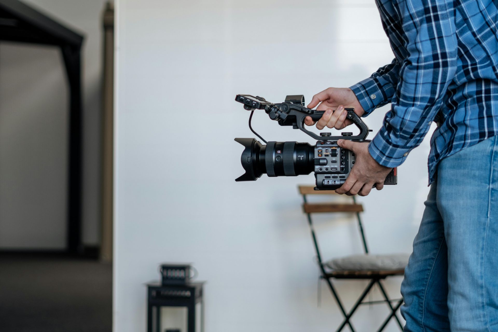 Person holding a professional video camera in a bright indoor room