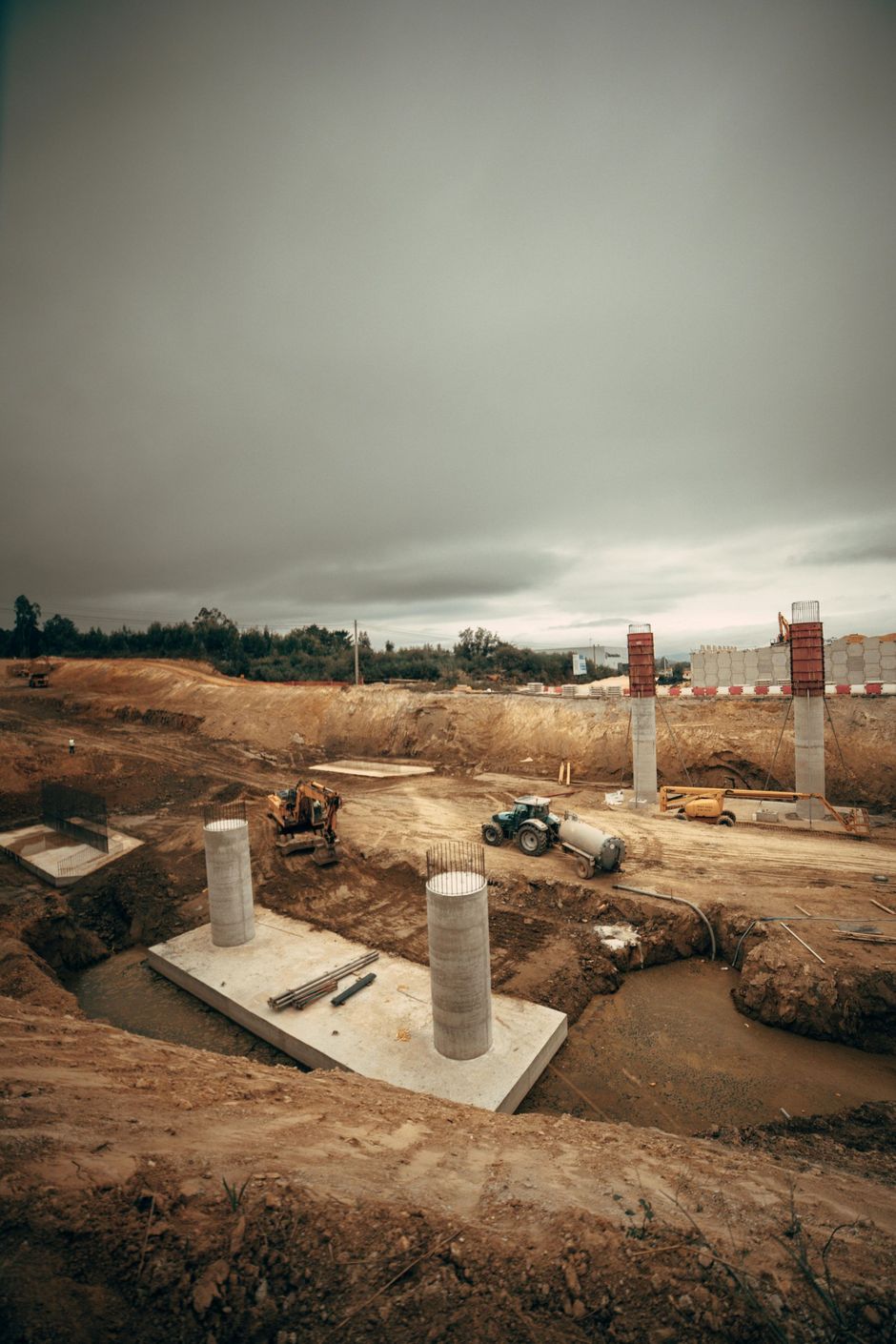 Concrete foundation columns at a construction site under a cloudy sky