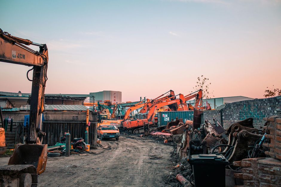 Construction site with excavators and dirt piles at sunset