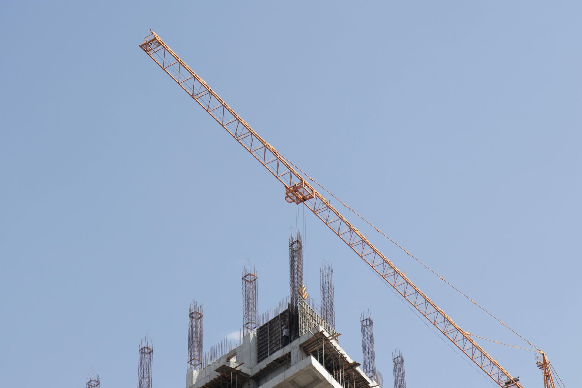 Construction crane above a building under construction against a clear blue sky