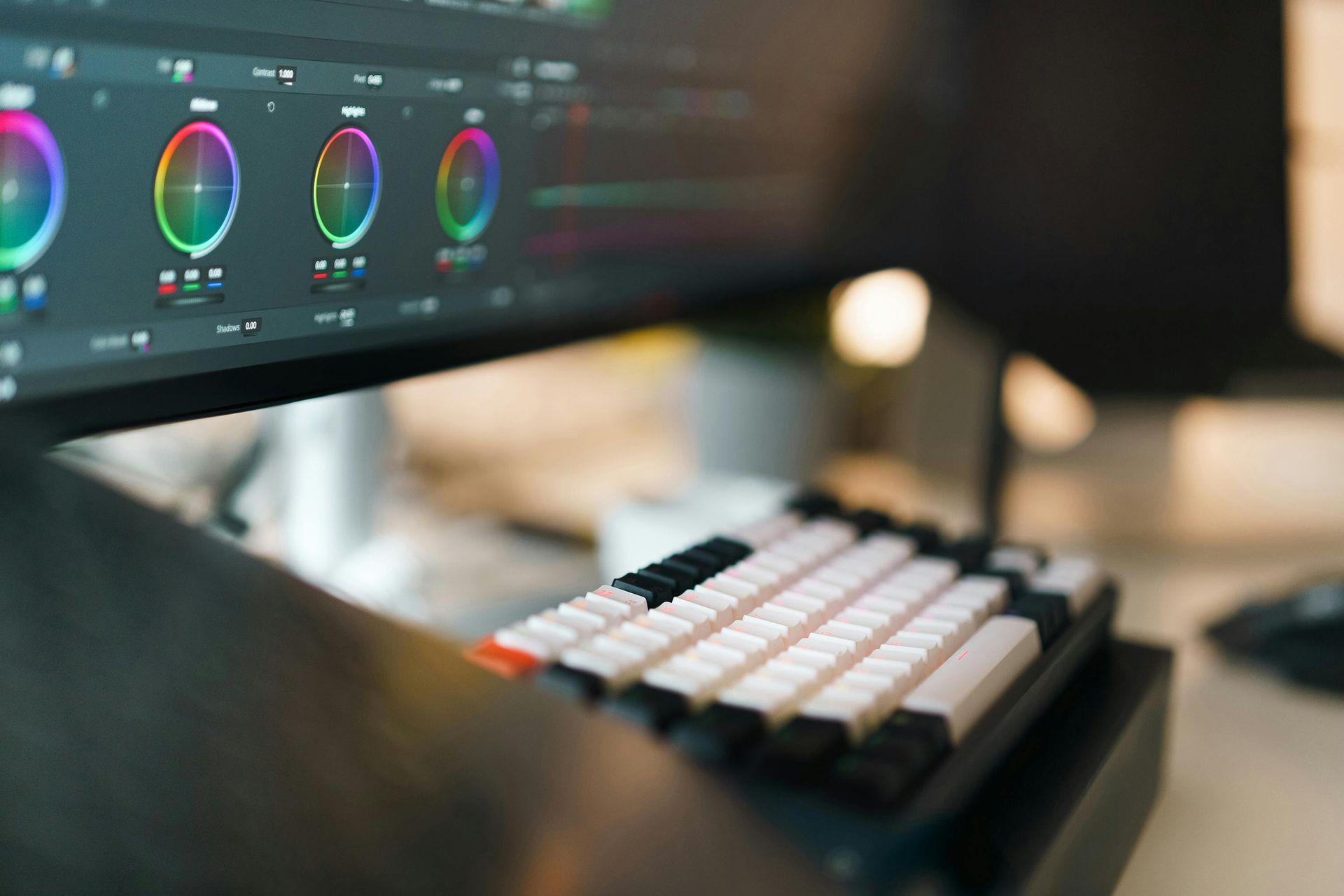 Color grading monitor and compact mechanical keyboard on a desk in a dark editing setup