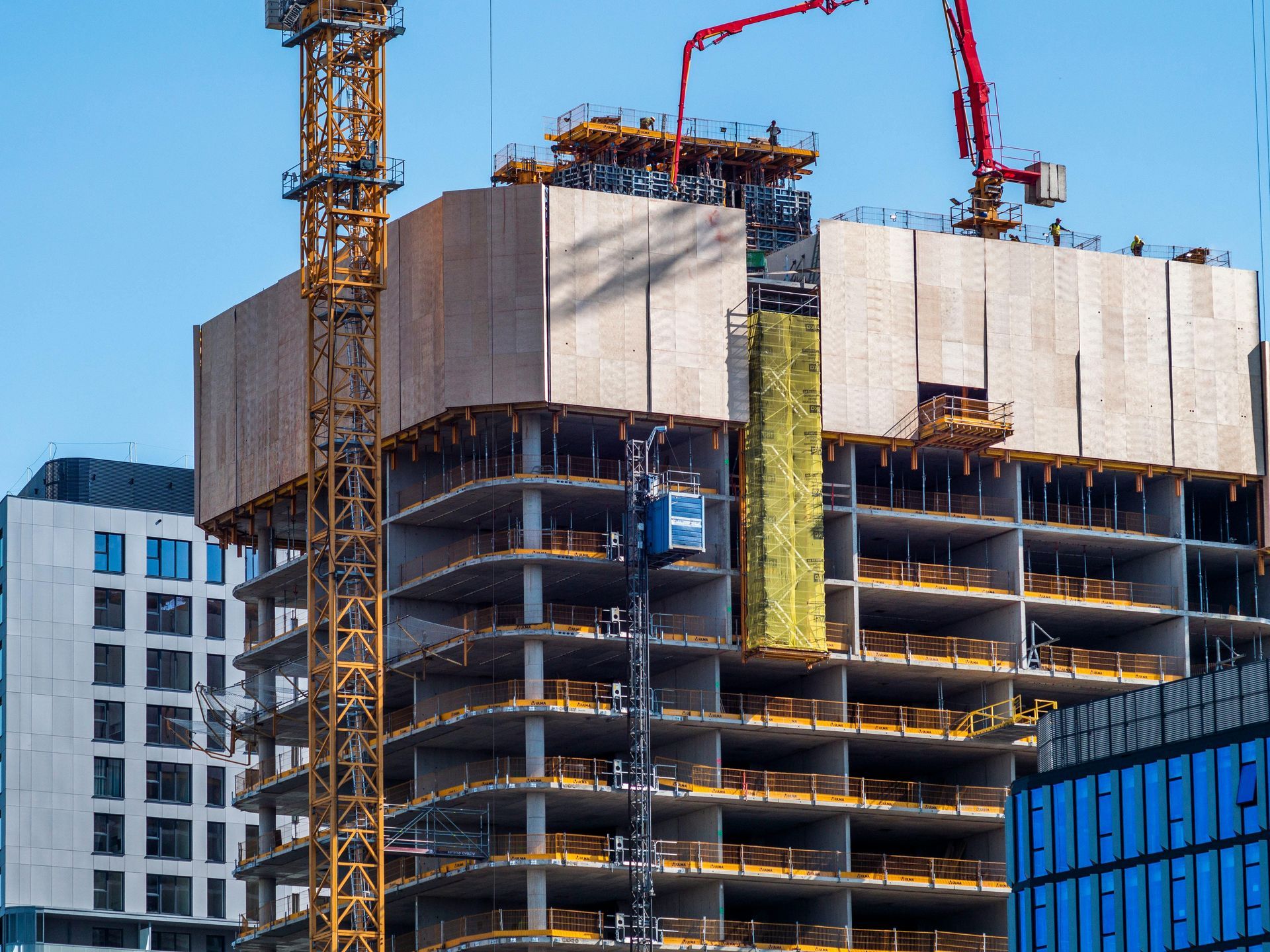 High-rise building under construction with cranes against a blue sky