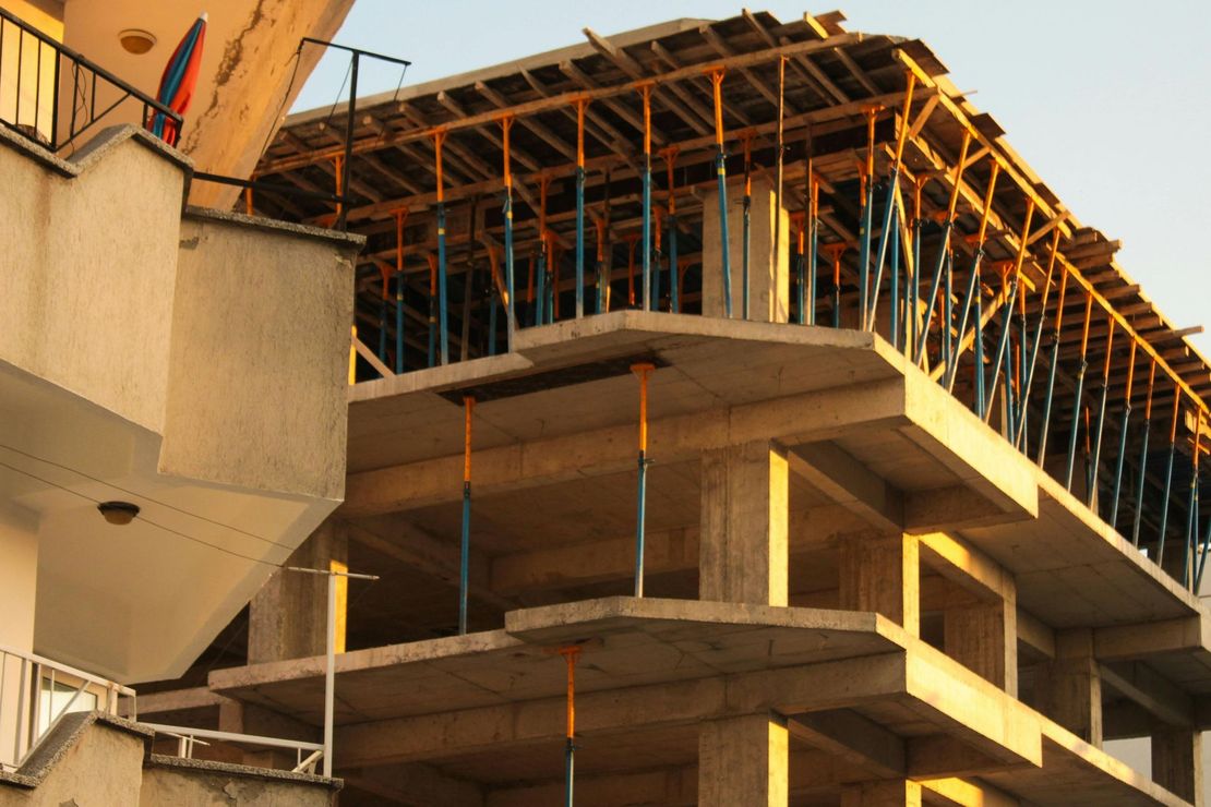 Partially built concrete building with exposed steel framing at sunset