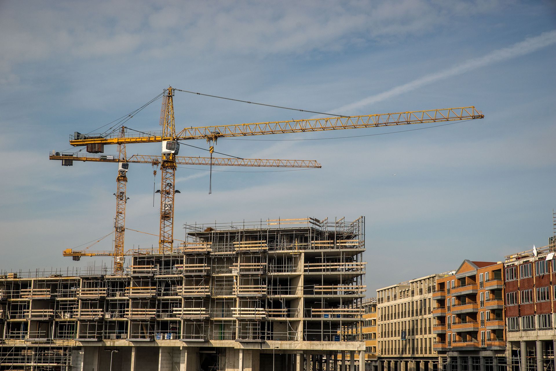 Commercial building under construction with tower cranes, marketing for general contractors