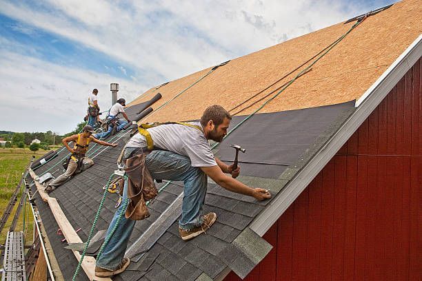 Four men performing roof repairs with tools, showcasing a professional roof repair contractor team.