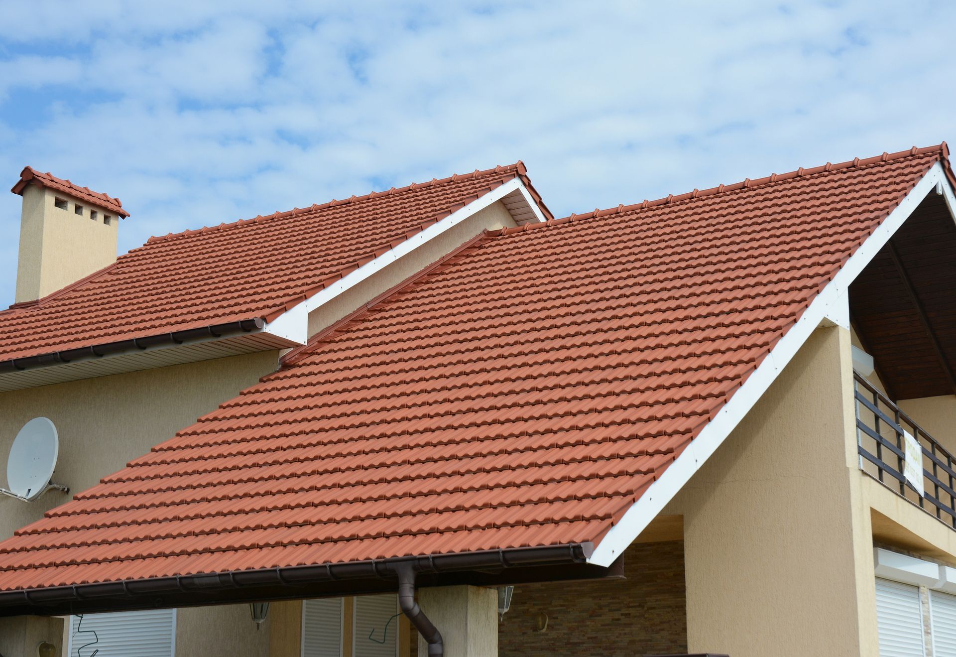 Residential house with red clay tile roof, gabled architecture, gutters, and clear blue sky home new.