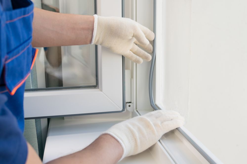 A Man Wearing Gloves is Working on a Window — Fast Glass & Glazing In Tamworth, NSW