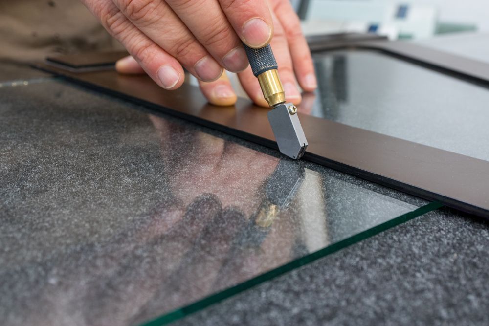 A Person is Cutting a Piece of Glass With a Glass Cutter — Fast Glass & Glazing In Tamworth, NSW