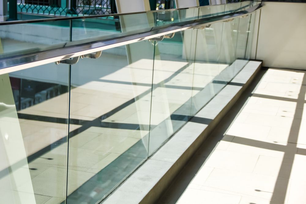Glass railing in bright sunlight, casting shadows on a light-coloured floor — Fast Glass & Glazing In Barraba, NSW