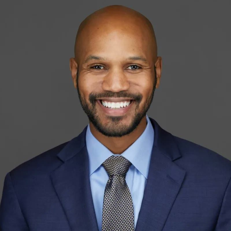 Dr. Charles C. Hines III, smiling, in a navy suit and tie