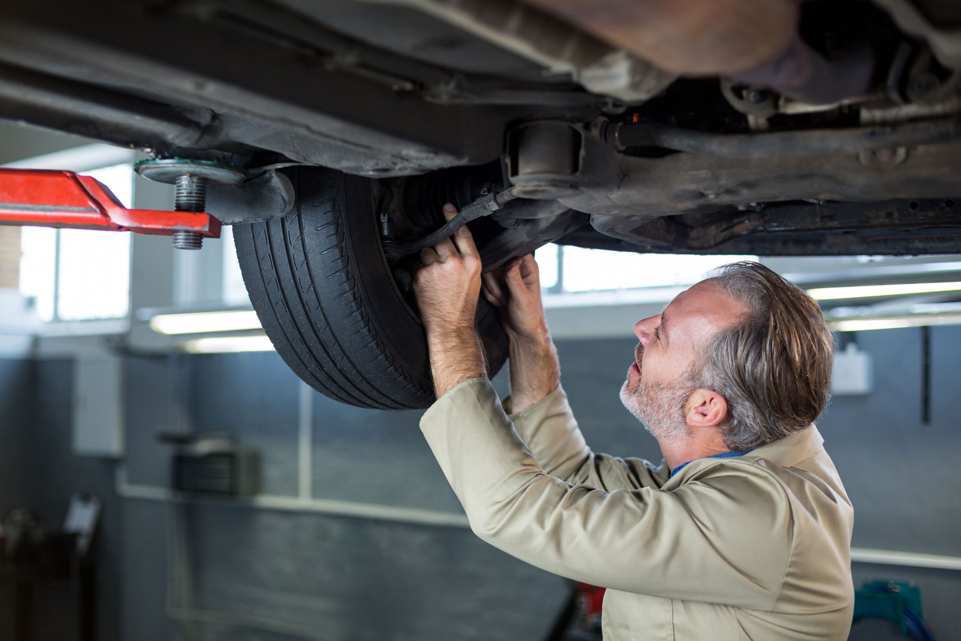 Mechanic inspecting undercarriage of a car on a lift in a repair shop